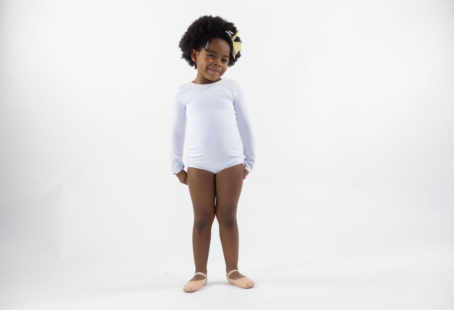 Little African American girl about age 5 wearing a white leotard made of a soft stretch fabric.