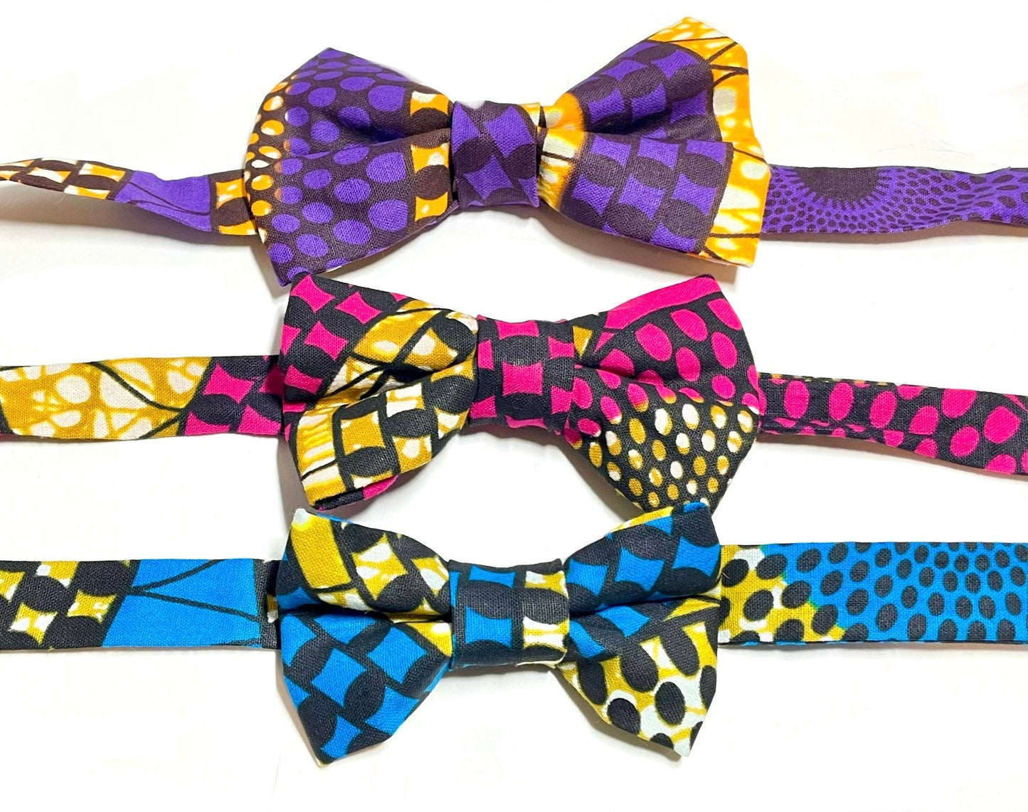 A selection of 3 African print bow ties. These bow ties are in the colors of fuchsia, purple and blue.