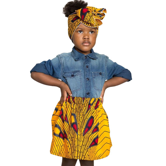 African American girl wearing an African print  yellow with red, and black design skirt and matching headwrap.